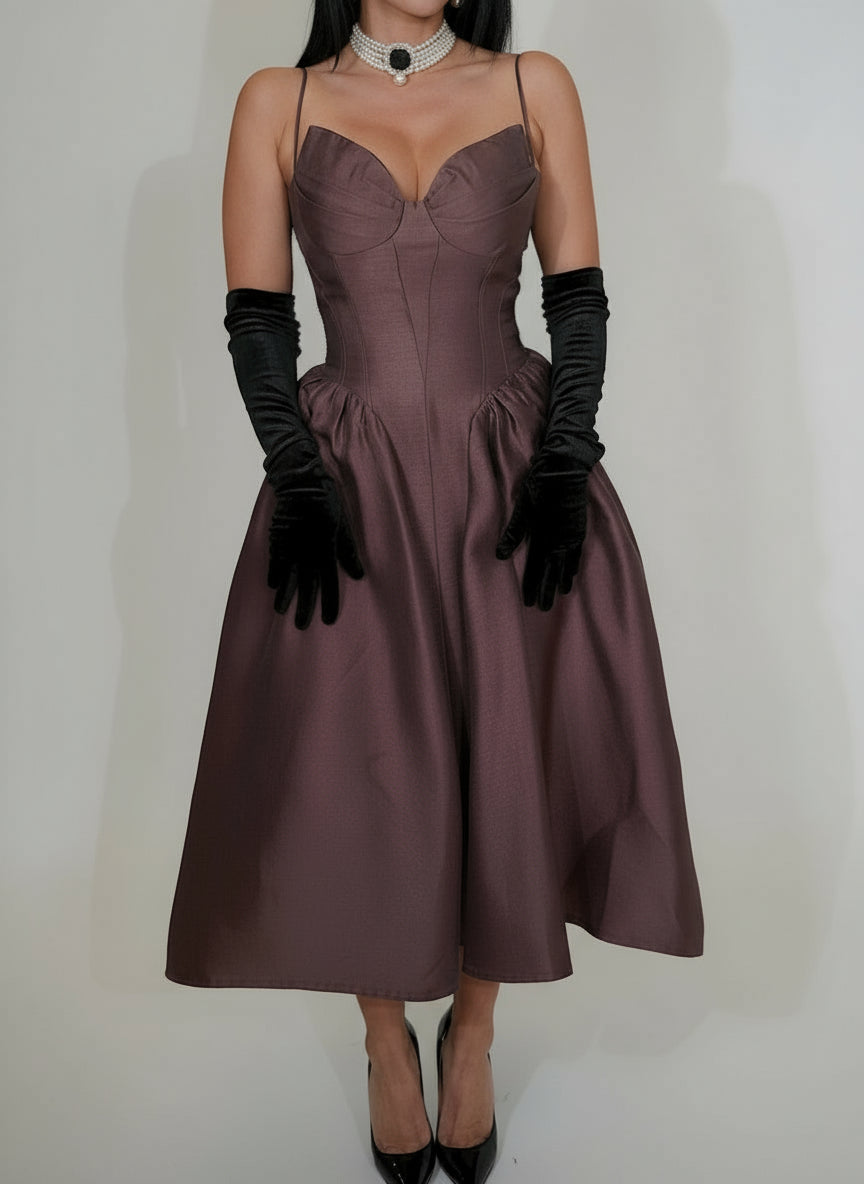Woman wearing a brown dress with black gloves on a plain background